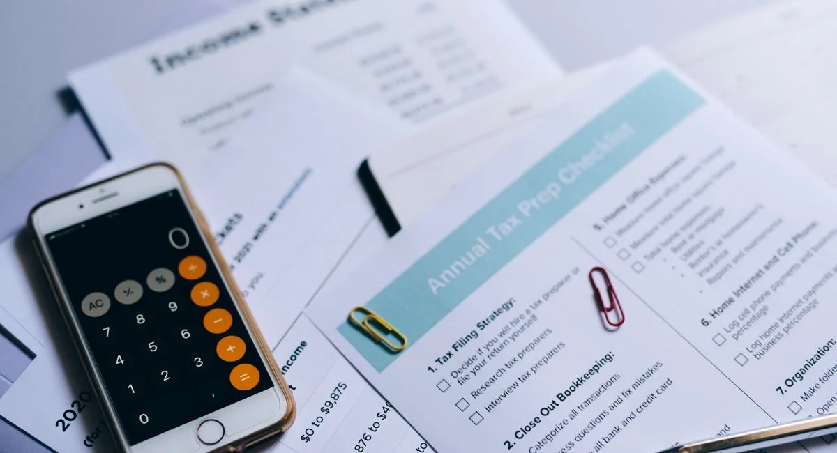 Tax preparation setup with documents, smartphone calculator, and checklist.