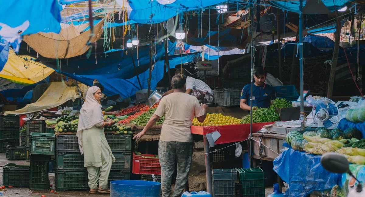 Bustling local market scene with fresh fruits and vegetables and diverse people engaging in commerce.