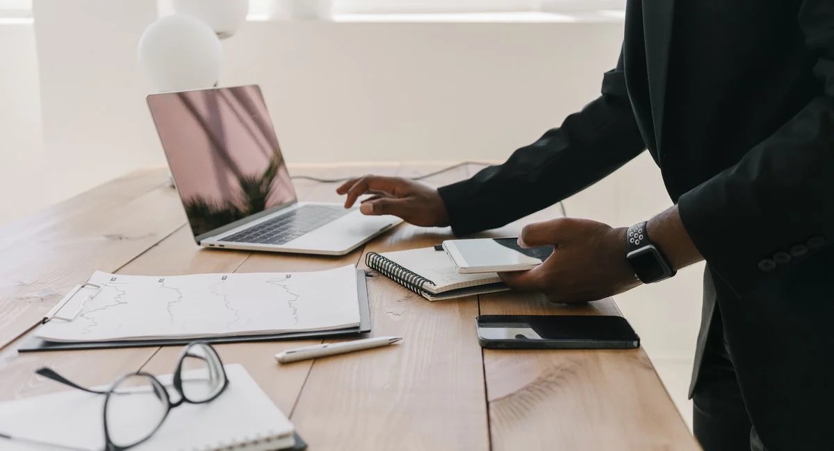 Professional workspace with a laptop, documents, and stationery on a wooden table.