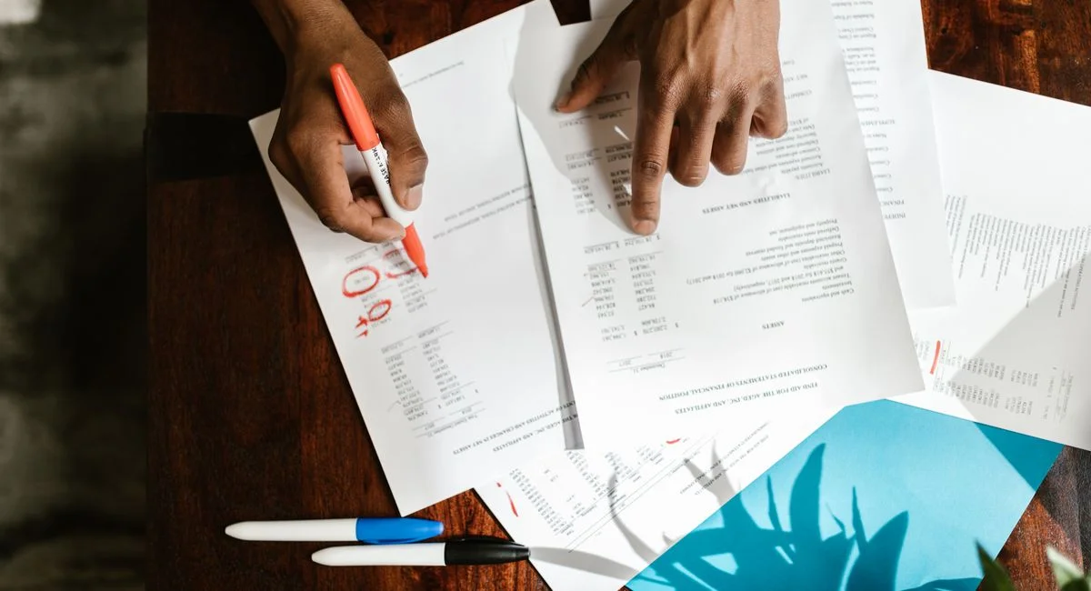 Overhead view of hands highlighting financial documents on a desk.
