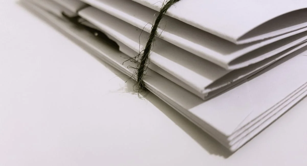 Pile of white envelopes tied with a green string, showcasing a minimalist design.