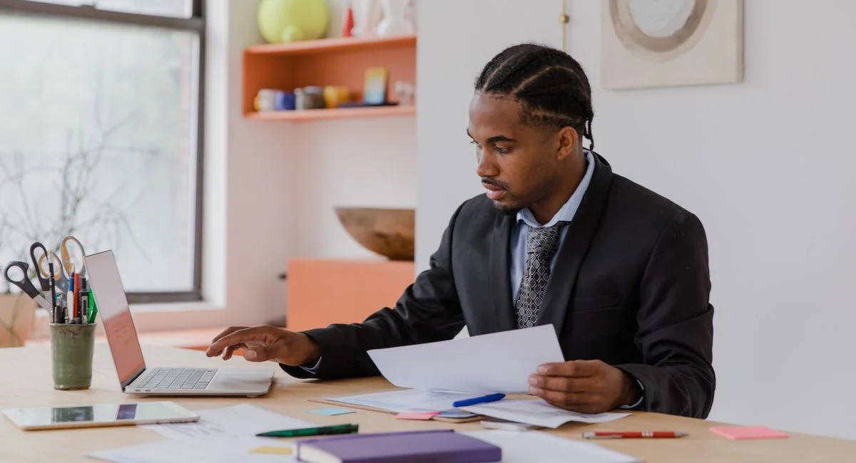 Focused businessman working with laptop and documents in a modern office setting.