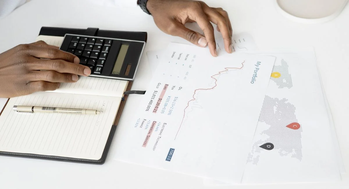 Overhead view of a person analyzing financial documents using a calculator for investment planning.