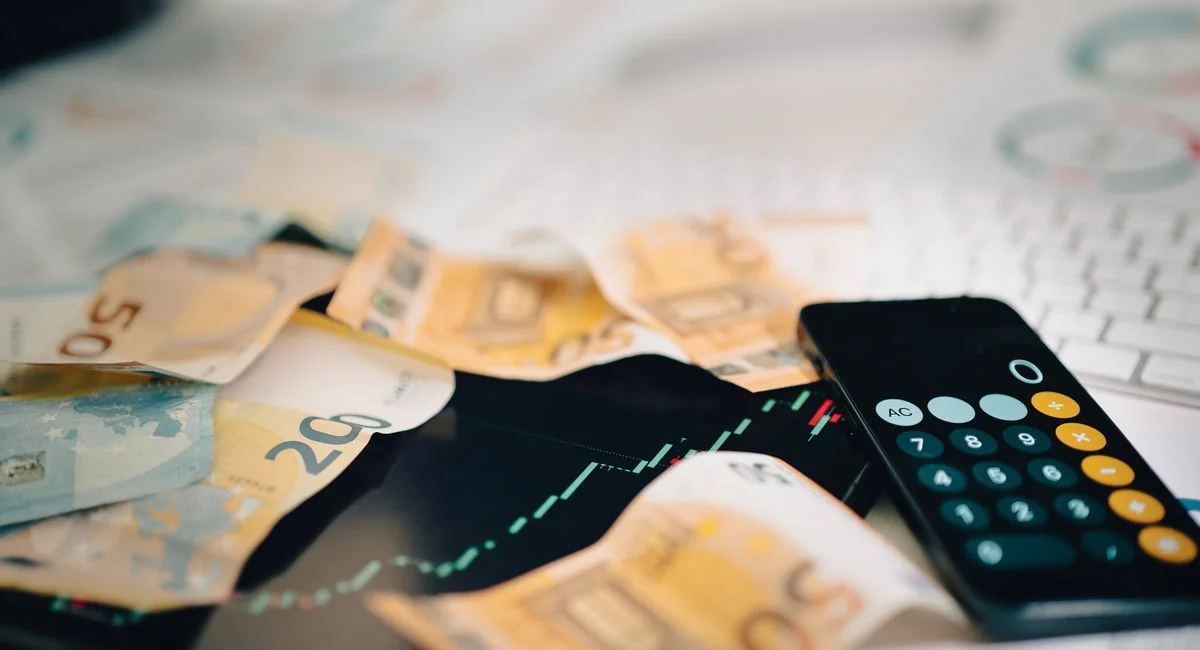 Euro banknotes scattered on a trading chart with a calculator, symbolizing finance and analysis.