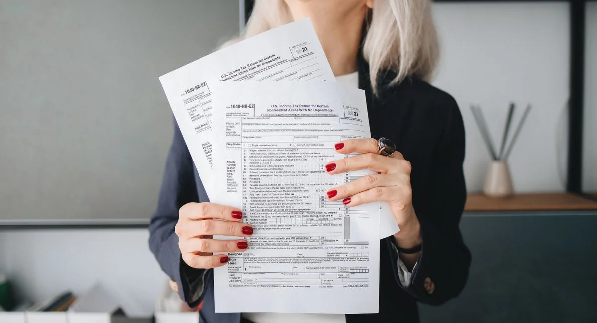Businesswoman holding tax documents, ready for filing or review, in a professional office setting.