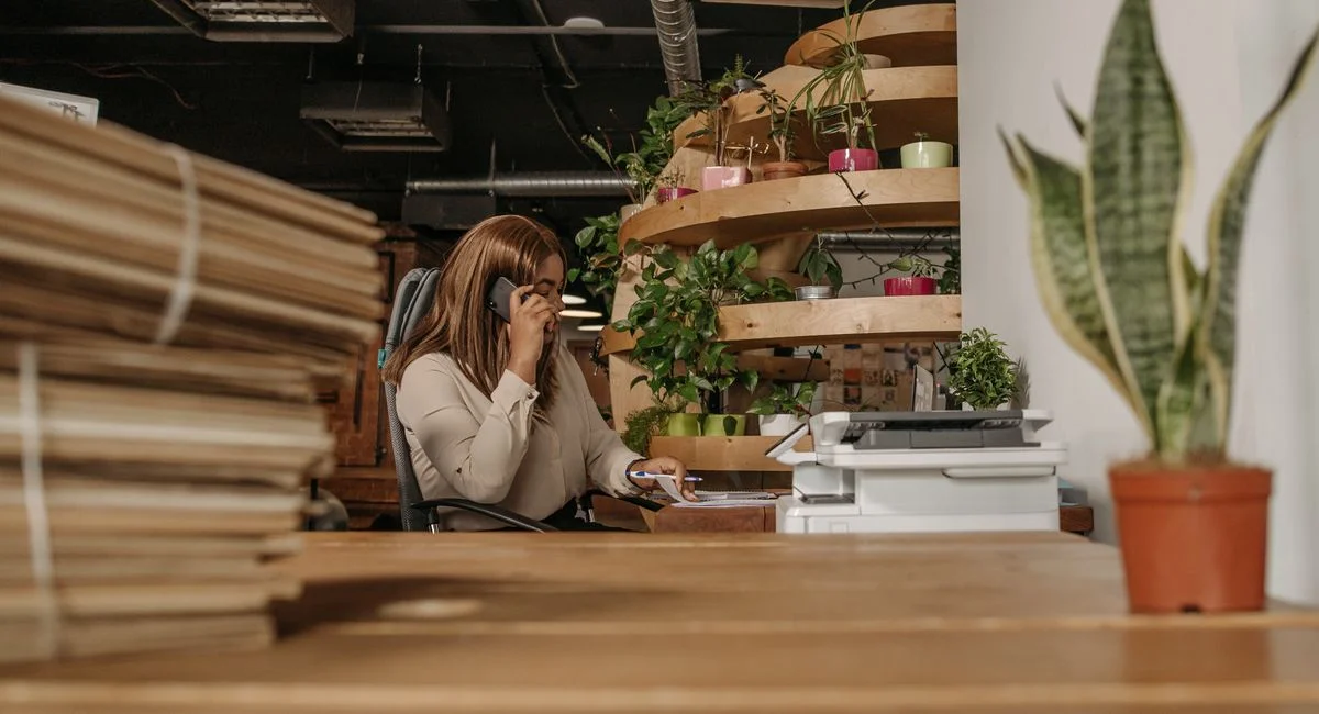 A woman making a phone call in an eco-friendly office with plants and wooden interiors.