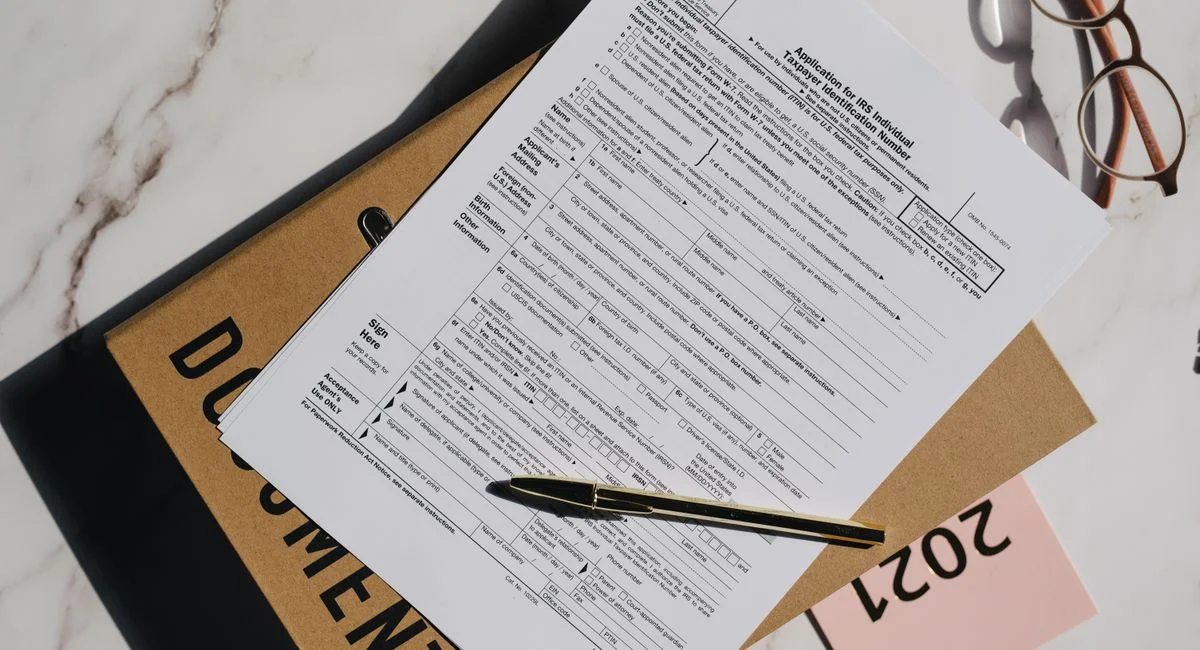 Top view of a tax form with a pen and eyeglasses on a marble surface, perfect for finance themes.