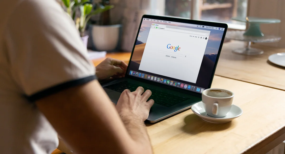 A person working on a laptop in a cozy indoor setting with a coffee cup on the table.
