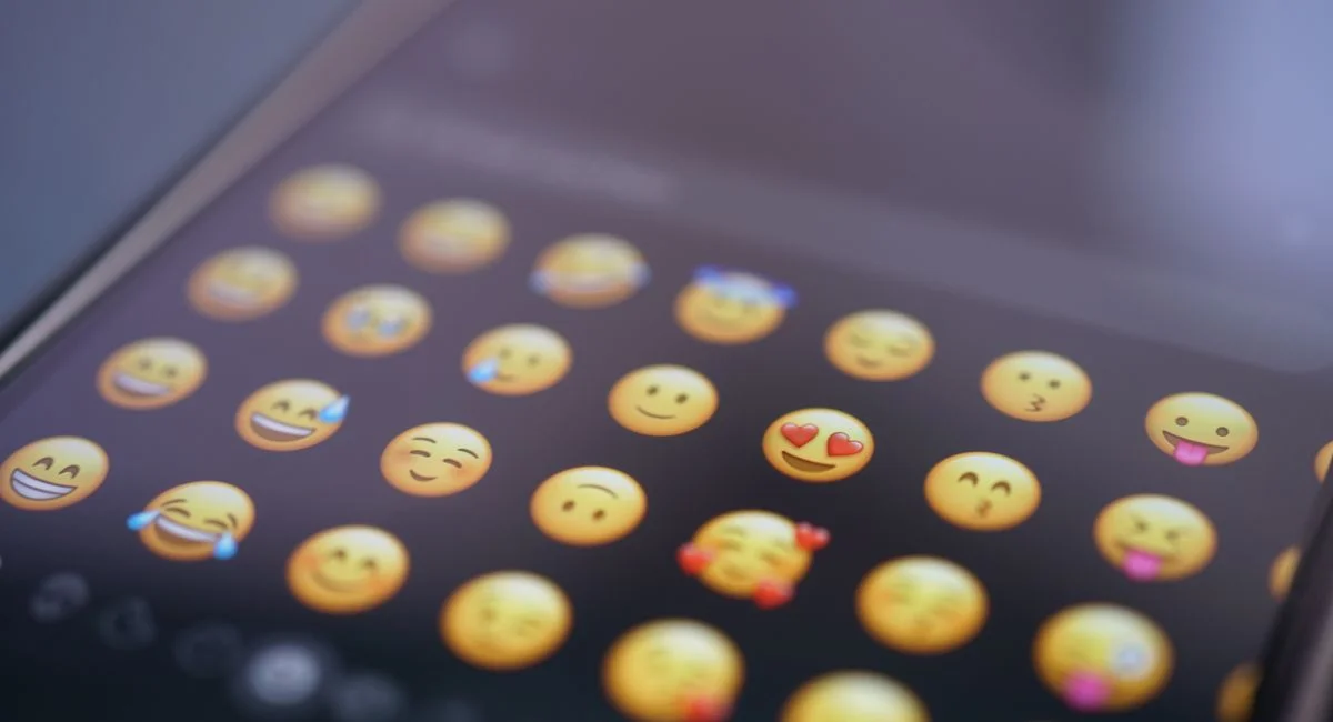 A close-up view of various emojis on a smartphone screen, symbolizing digital communication and social media use.