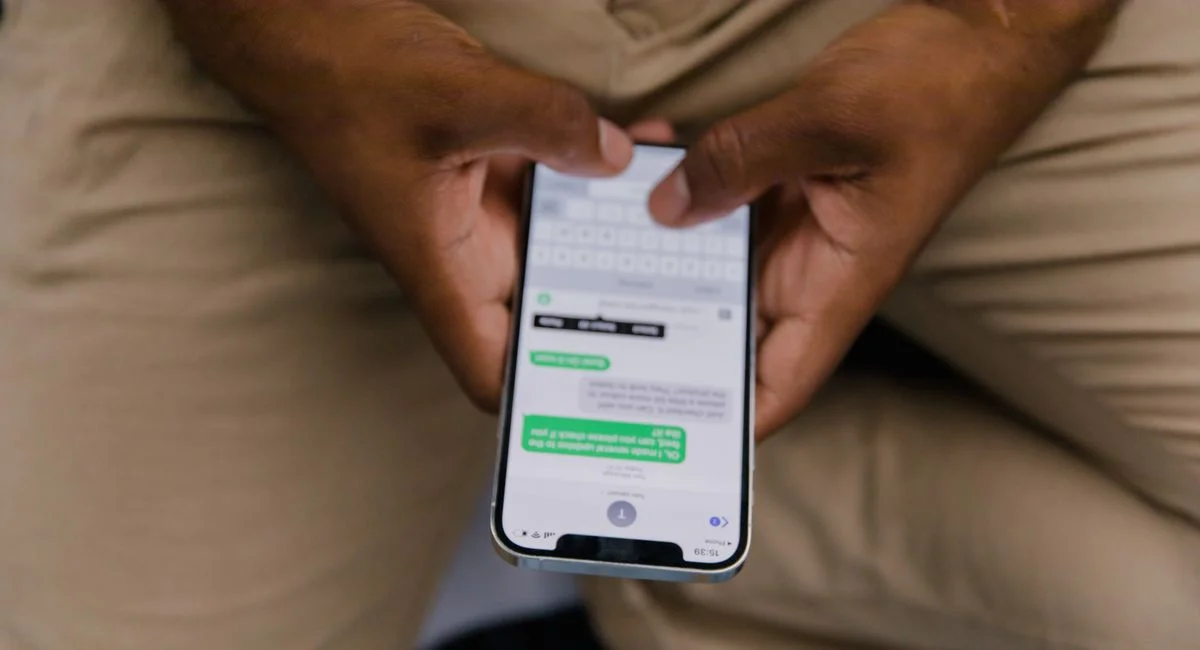 Close-up view of hands texting on a smartphone, focusing on the screen displaying messages.