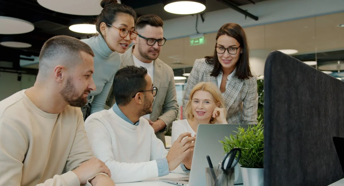 Diverse team working together on a project in a modern office setting, engaging with technology.