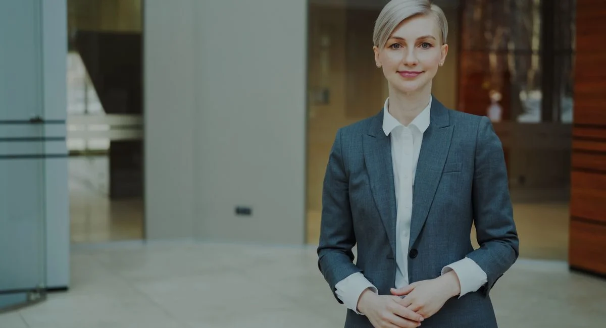 Confident businesswoman in a suit standing indoors in an elegant office setting.