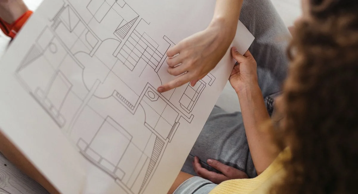 Two people reviewing and discussing a detailed architectural floor plan.