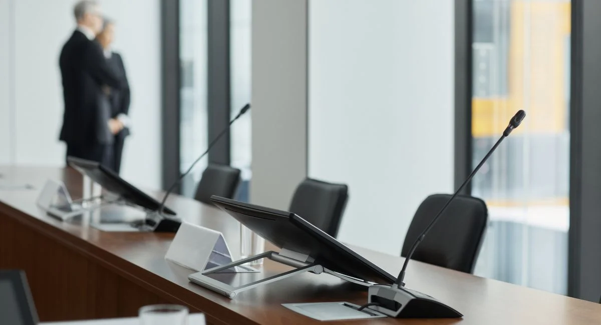 Sleek conference room setup with microphones, digital displays, and modern design elements.