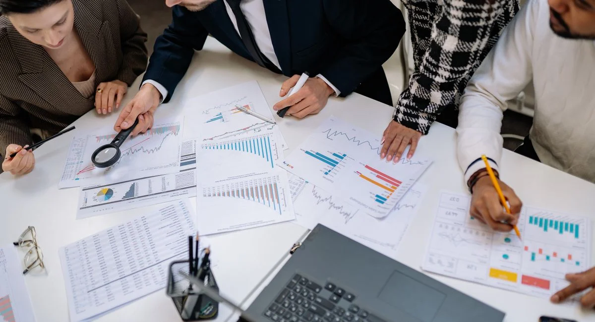 A group of professionals reviewing financial charts in an office meeting setting.